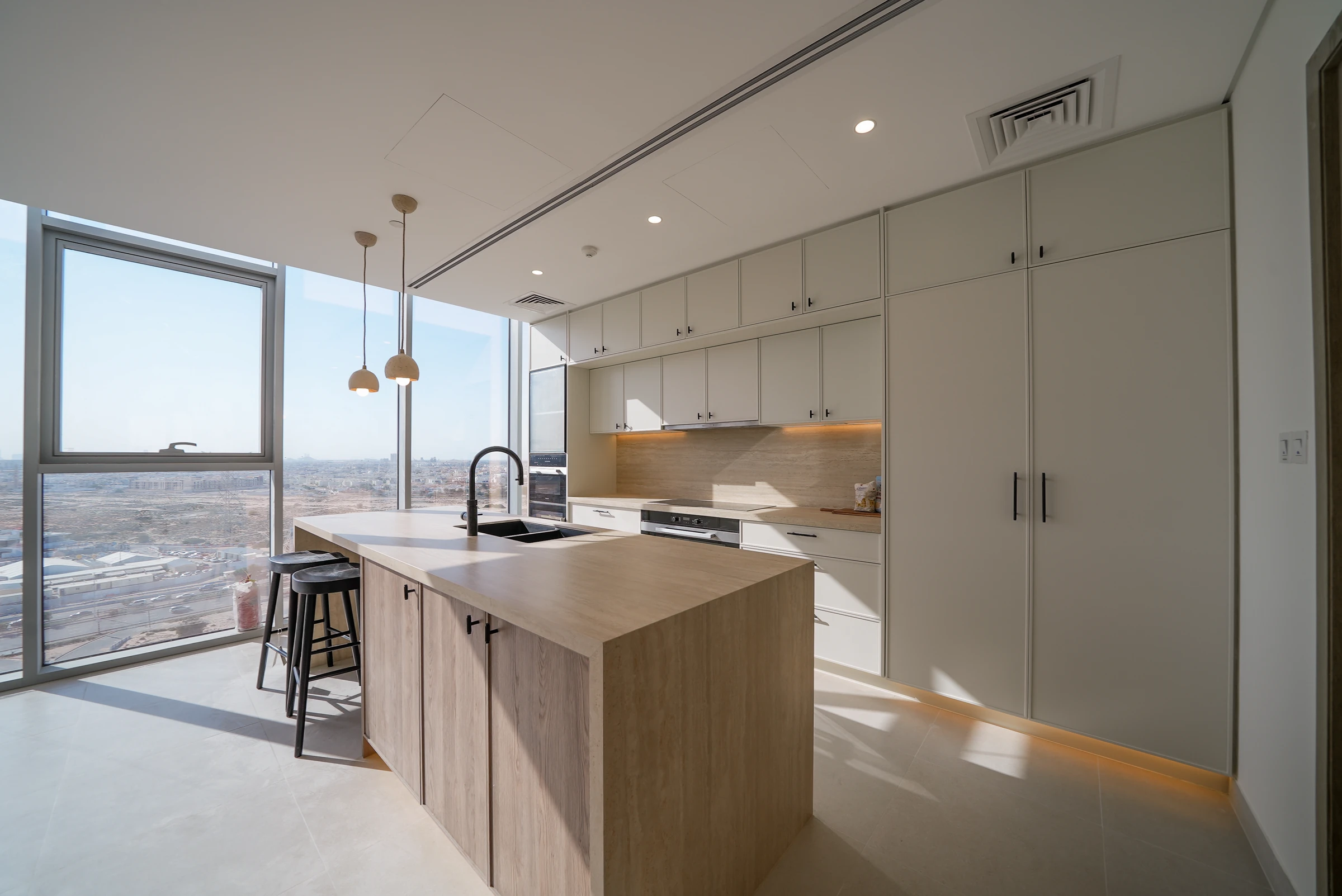 Warm wood and white kitchen with floor-to-ceiling windows by Vigilant Kitchens in Damac Lagoon Views